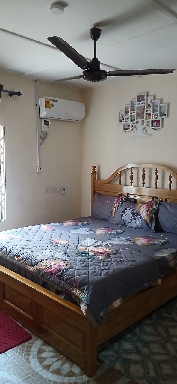Guest room with floral bedding, a wooden headboard and a ceiling fan.