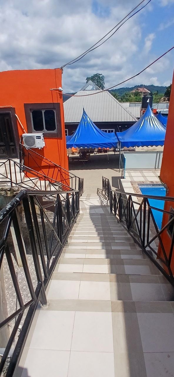 Tiled poolside walkway with metal railings and a blue canopy.