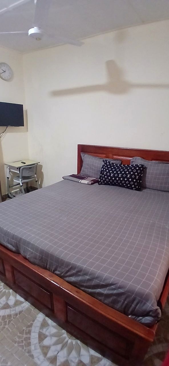 Guest room with grey bedding, a wooden bed and a bedside table.