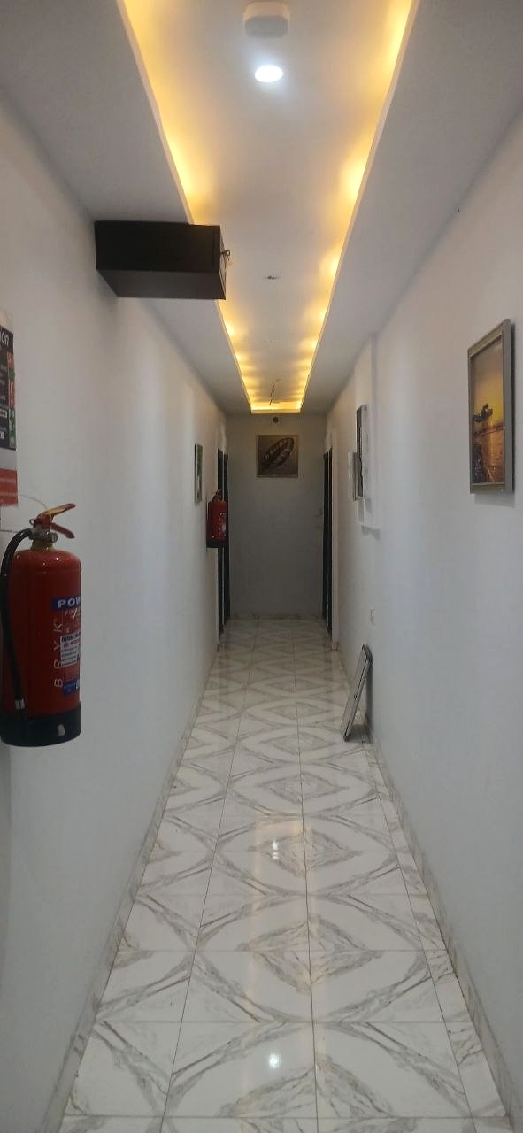 Guest-room corridor with illuminated ceiling and tiled floor.