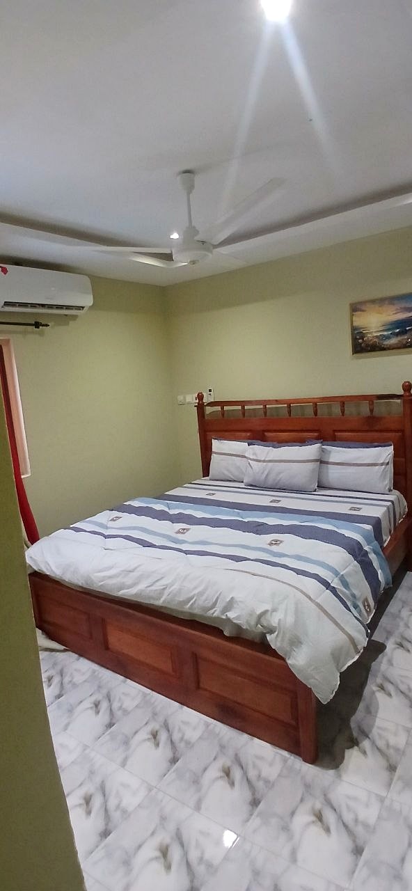 Guest room with striped bedding, a wooden headboard and air conditioner.