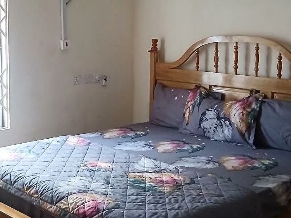 Bed with floral bedding and a curved wooden headboard.