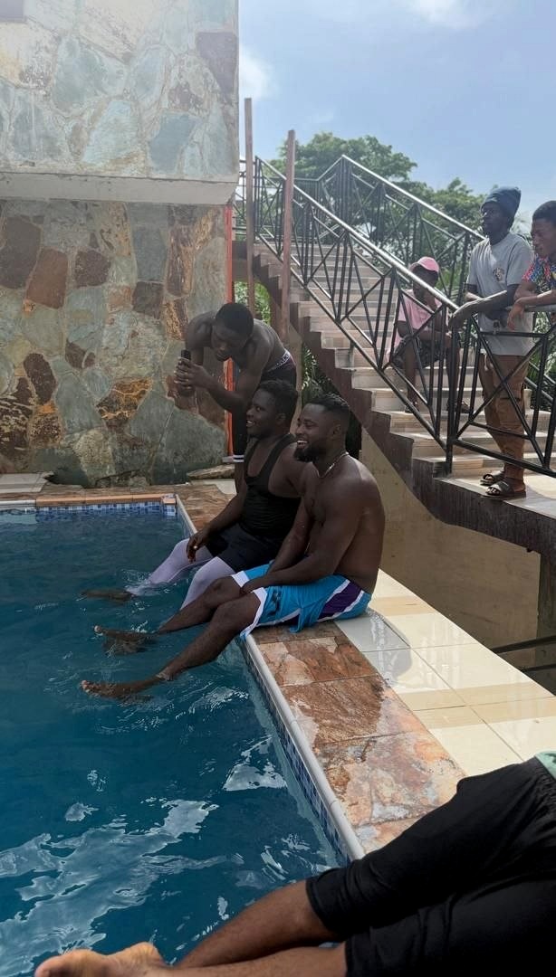 Guests sitting at the pool edge beside a stone wall.