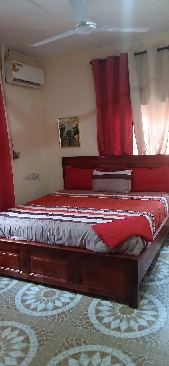 Guest room with red curtains, a wooden bed and red-and-white bedding.