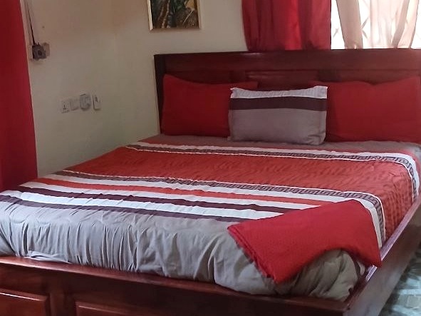 Wooden bed with red-and-white bedding beside red curtains.