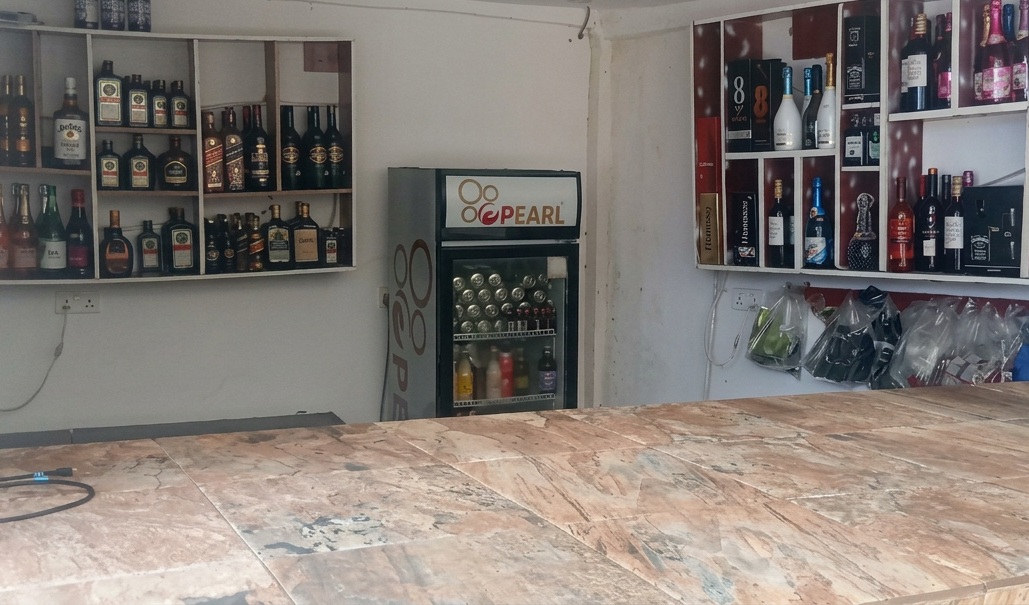Pub counter with bottle shelves and framed wall displays.